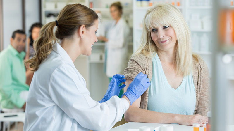 A female doctor or pharmacist is administering the shot to senior woman