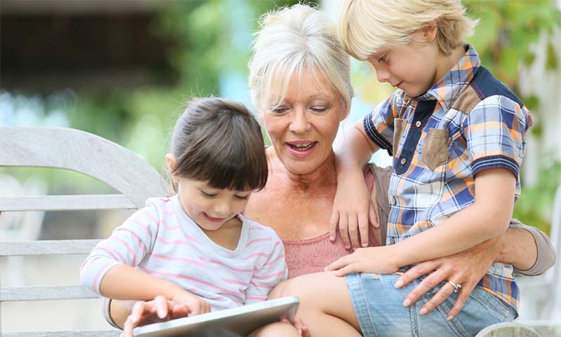 grandmother with grandchildren looking at digital tablet