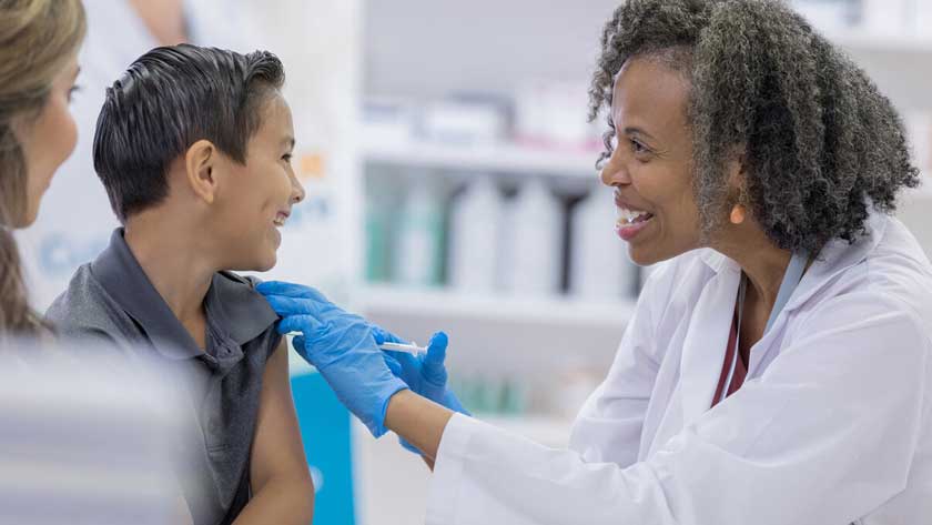 pharmacist administering vaccine to young boy