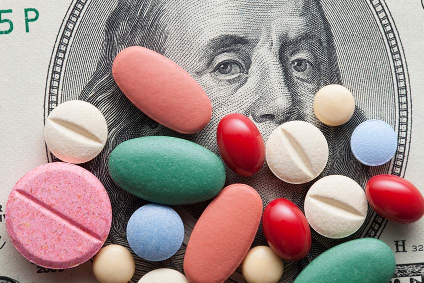 assorted colorful pills on top of a one hundred dollar bill