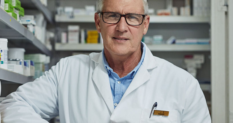Mature pharmacist standing at counter thinking about succession planning