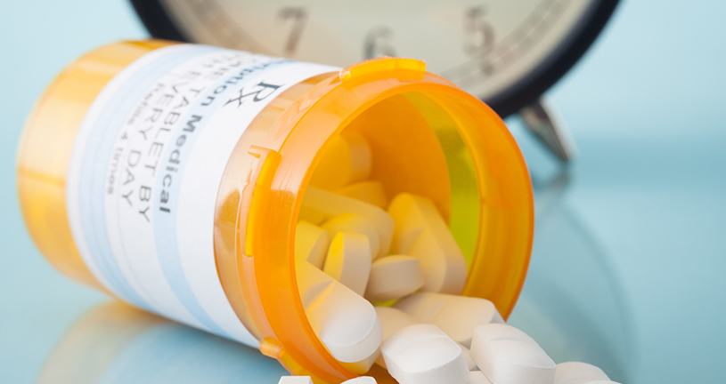 Pill bottle in front of clock - pharmacy operations