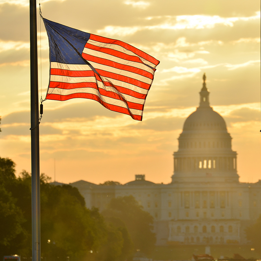 us flag in front of capitol sunset