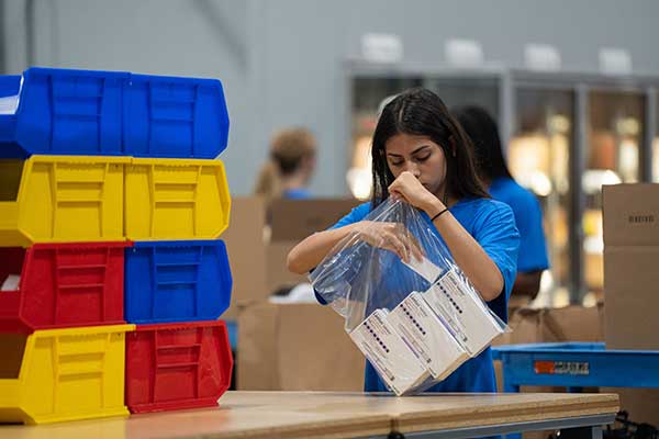ipc employee packing phramacy order in bag before shipping