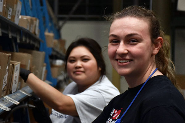 IPC warehouse employees posing for camera while picking product for member order