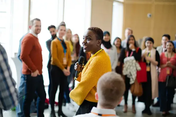 Smiling female speaker with microphone in room full of people for pharmacy marketing