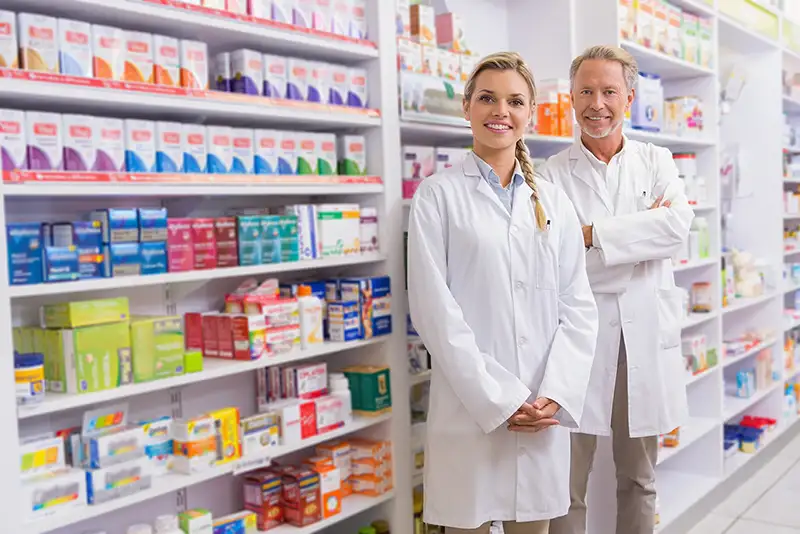 Pharmacist with his trainee standing and smiling at camera