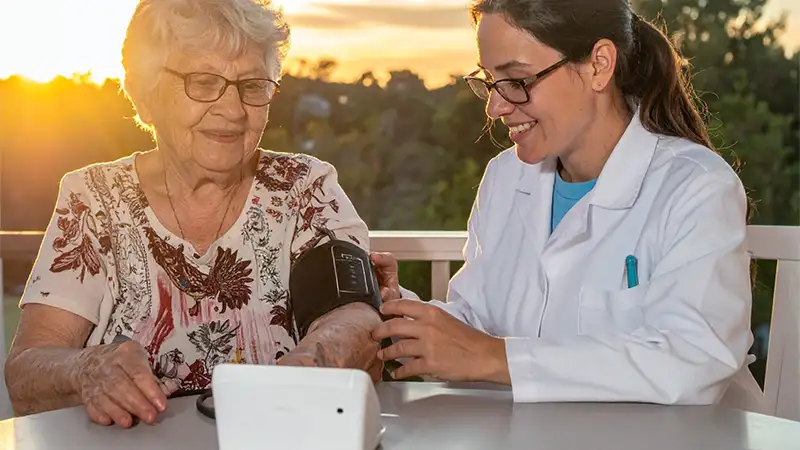elderly woman with pharmacist setting up remote patient monitoring equipment