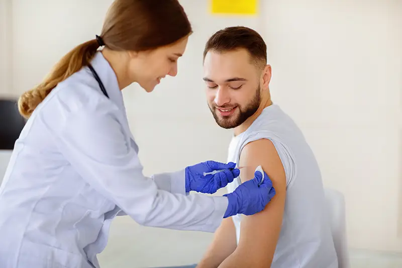 pharmacist vaccinating young male patient